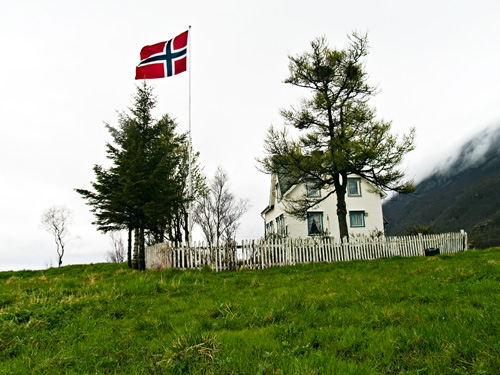 House in field flying norwegian flag